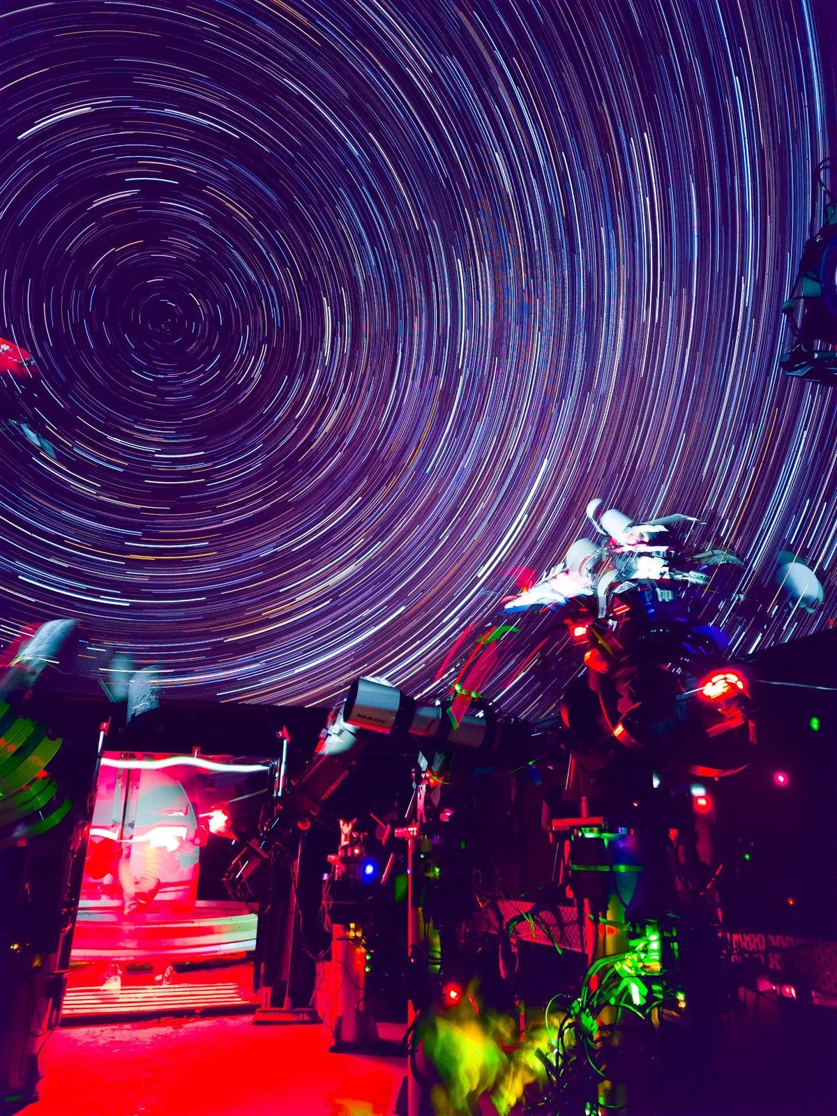 Circular star trails around the south celestial pole above telescopes in an observatory